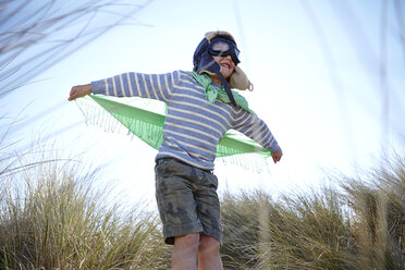 Young boy on beach, wearing fancy dress, pretending to fly - CUF27227