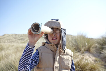 Young boy on beach, looking through pretend telescope - CUF27233