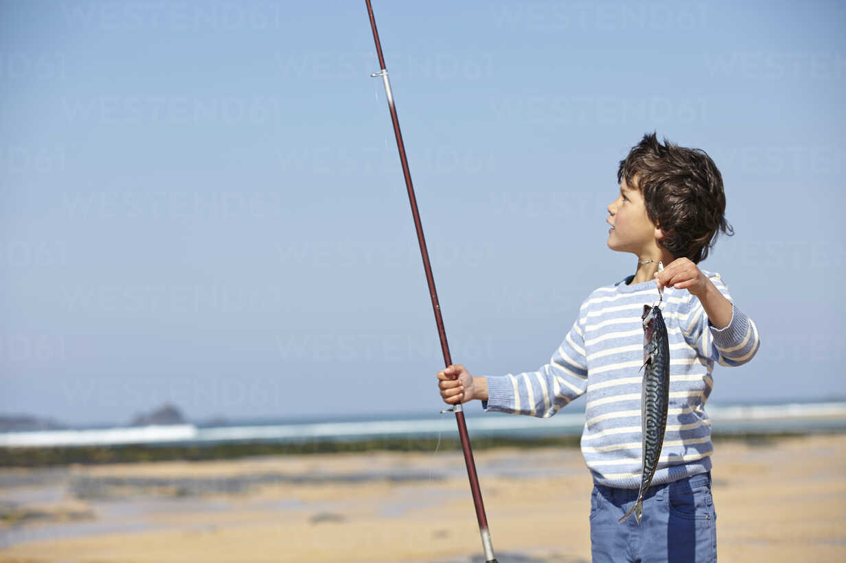 Young boy holding up fishing rod and fish stock photo