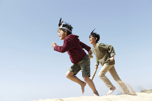 Two boys, wearing fancy dress, playing on sand - CUF27267