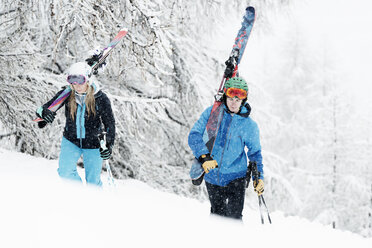 Man and woman walking in snow with skis - CUF27270