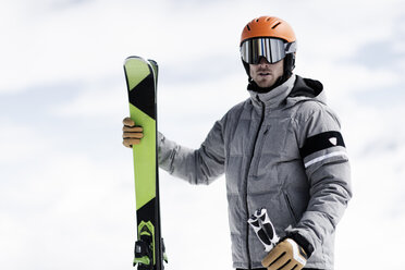 Mann mit Helm und Skibrille hält Skier, Porträt - CUF27276
