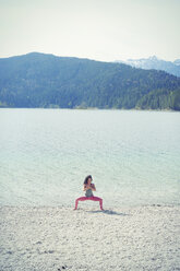 Mittlere erwachsene Frau, neben dem See, in Yogaposition - CUF27293