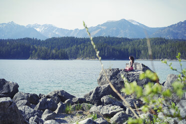 Mid adult woman, sitting on rock, in yoga position - CUF27326