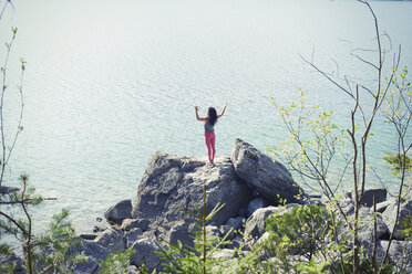 Mittlere erwachsene Frau, stehend auf einem Felsen am See, in Yoga-Position, Rückansicht - CUF27328