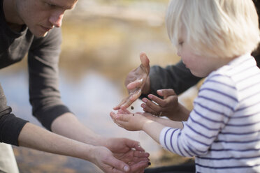 Boy catching water droplets in cupped hands - CUF27331