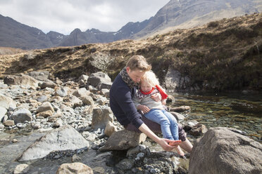 Vater und Sohn sitzen auf Felsen, Fairy Pools, Isle of Skye, Hebriden, Schottland - CUF27344