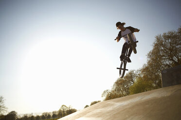 Junger Mann, der in der Luft einen Stunt auf einem BMX im Skatepark macht - CUF27355