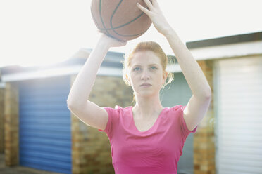 Porträt einer Frau, die einen Basketball über dem Kopf hält - CUF27361