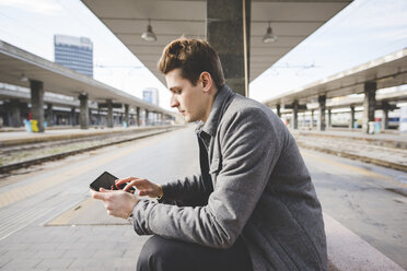 Porträt eines jungen Geschäftsmannes, der am Bahnhof ein digitales Tablet benutzt. - CUF27376