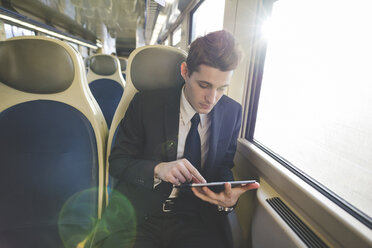 Portrait of young businessman commuter using digital tablet on train. - CUF27383