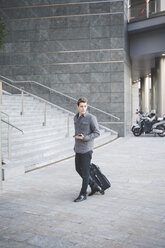 Young businessman commuter walking with suitcase. - CUF27386