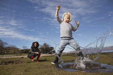 Boy splashing in puddle - CUF27391