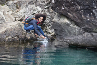 Mid adult woman crouching by pond - CUF27398