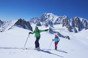 Male and female skiers pointing from Mont Blanc massif, Graian Alps, France - CUF27415