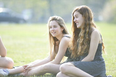 Teenager-Mädchen sitzen im Park und unterhalten sich - CUF27460
