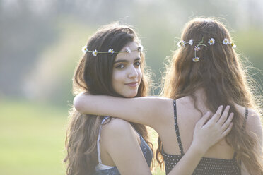 Rückansicht von zwei Teenager-Mädchen mit Gänseblümchen-Kopfschmuck im Park - CUF27467