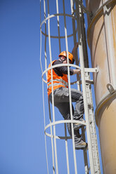 Worker climbing smoke stack ladder - CUF27490