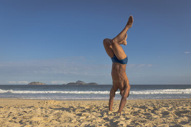 Mittlerer erwachsener Mann macht Handstand am Strand, Rio de Janeiro, Brasilien - CUF27492