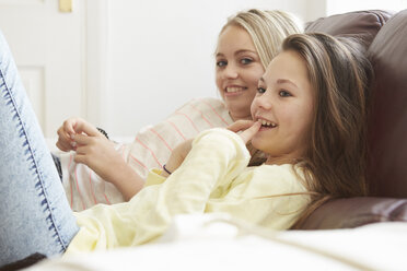Two girls watching tv from sofa - CUF27549
