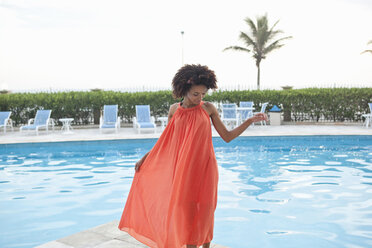 Junge Frau in orangefarbenem Kleid am Hotelpool, Rio De Janeiro, Brasilien - CUF27565