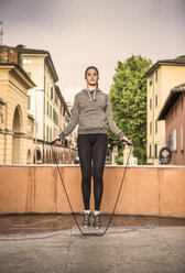 Front view of woman wearing sports clothes using skipping rope - CUF27621