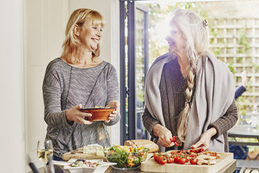 Two female friends preparing foo in kitchen - CUF27645