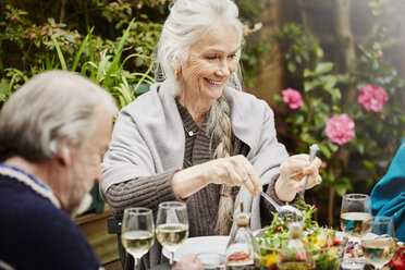 Senior friends eating meal in garden - CUF27647