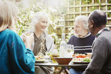 Senior friends eating meal in garden - CUF27650