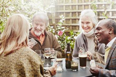 Ältere Freunde trinken und spielen Karten im Garten - CUF27654