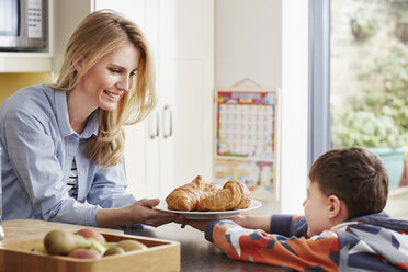Mutter gibt ihrem Sohn ein Croissant - CUF27668
