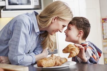 Junge mit Croissant in der Hand, von Angesicht zu Angesicht mit seiner Mutter - CUF27669