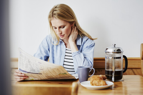 Mid adult woman reading newspaper stock photo