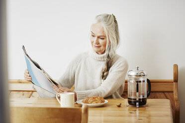 Ältere Frau liest beim Frühstück Zeitung - CUF27675