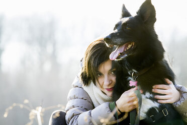 Porträt einer mittelalten Frau, die ihren Hund umarmt - CUF27693