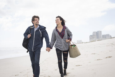 Romantic young couple strolling on windswept beach, Western Cape, South Africa - CUF27716