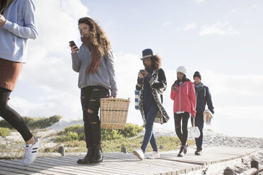Reihe junger Erwachsener, die an der Strandpromenade entlang schlendern und Smartphones lesen, Westkap, Südafrika - CUF27727