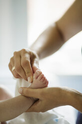 Close up of mothers hand cleaning baby sons feet - CUF27786
