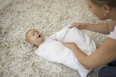 Einwickeln Schritt 5: Die Mutter wickelt den kleinen Jungen mit einer Decke ein und deckt ihn zu - CUF27791