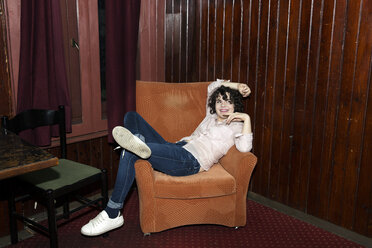 Portrait of young woman reclining on armchair on night out in bar - CUF27825