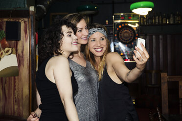 Drei erwachsene Freundinnen machen ein Smartphone-Selfie in einer Bar - CUF27826