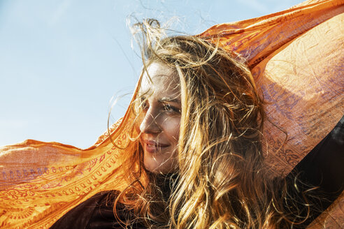 Porträt einer lächelnden Frau mit wehendem Haar, die ein Tuch hält - FMKF05132