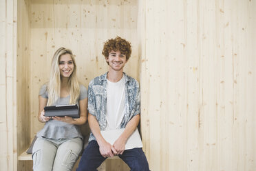 Arbeitskollegen nutzen ein digitales Tablet in einem holzgetäfelten Sitzbereich - CUF27868