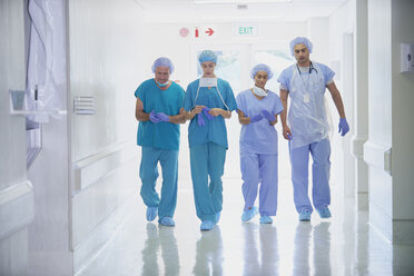 Four medical staff wearing scrubs walking in hospital corridor - CUF27908