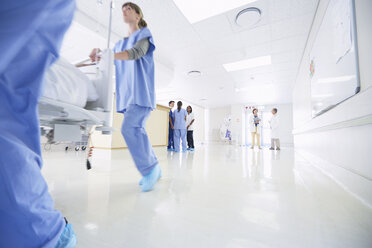 Sanitäter und Sanitäterinnen schieben ein Krankenhausbett eilig den Korridor entlang - CUF27912
