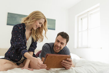 Ehepaar auf dem Bett mit digitalem Tablet lächelnd - CUF27924