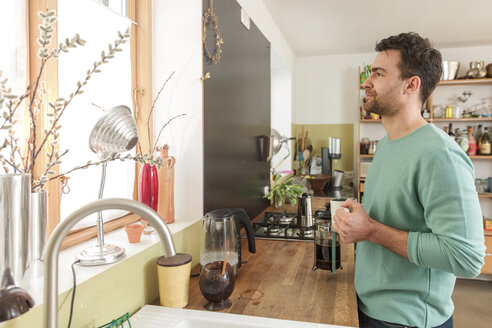 Mann in Küche mit Kaffeetasse und Blick aus dem Fenster - CUF27947