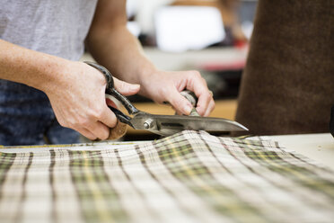 Woman cutting fabric in leather jacket manufacturers, close-up - CUF27979