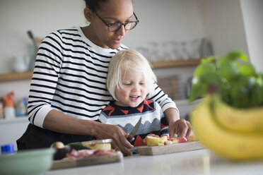 Mutter hilft Sohn bei der Zubereitung von Essen in der Küche - CUF28015
