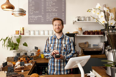 Porträt eines Kaffeehauskellners mit einem Kartenautomaten hinter dem Tresen - CUF28071